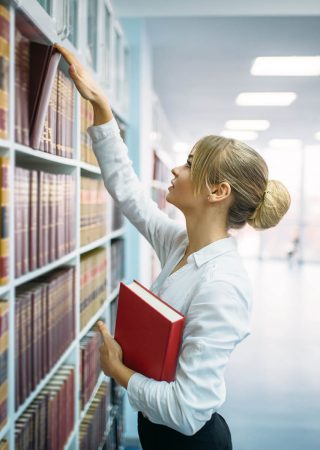 female-student-looking-book-at-the-shelf-library-72ZBLXJ.jpg